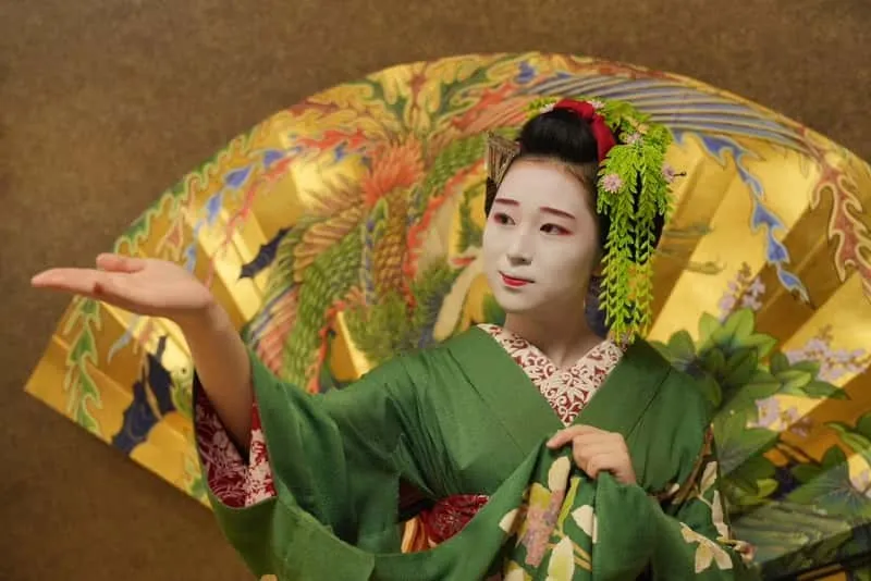 Maiko playing a traditional ozashiki game with guests during a geisha show in Kyoto's Gion district, Japan